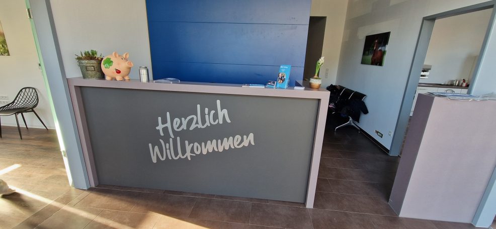 Empfangstresen mit der Aufschrift "Herzlich Willkommen" in einem modernen Raum.